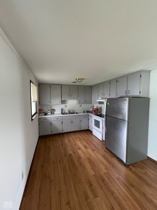 kitchen with gray cabinetry, stainless steel fridge, hardwood / wood-style floors, and electric range