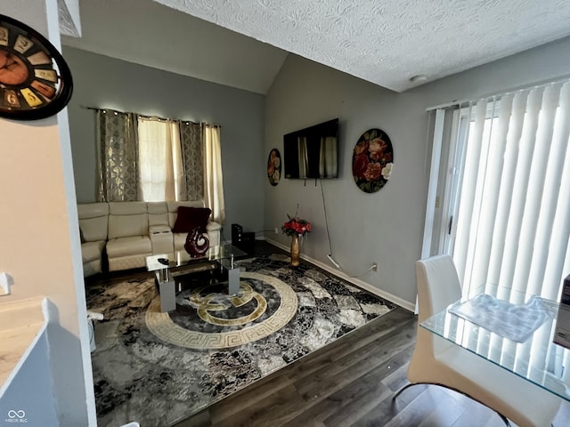 living room featuring vaulted ceiling, dark hardwood / wood-style floors, and a textured ceiling