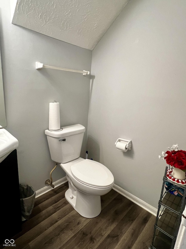 bathroom featuring vanity, wood-type flooring, a textured ceiling, and toilet