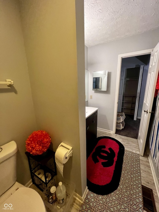 bathroom featuring vanity, a textured ceiling, and toilet