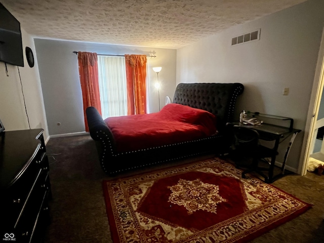 bedroom with a textured ceiling and dark carpet