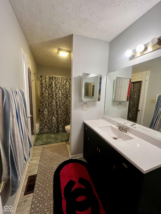 bathroom featuring hardwood / wood-style floors, vanity, a shower with shower curtain, toilet, and a textured ceiling