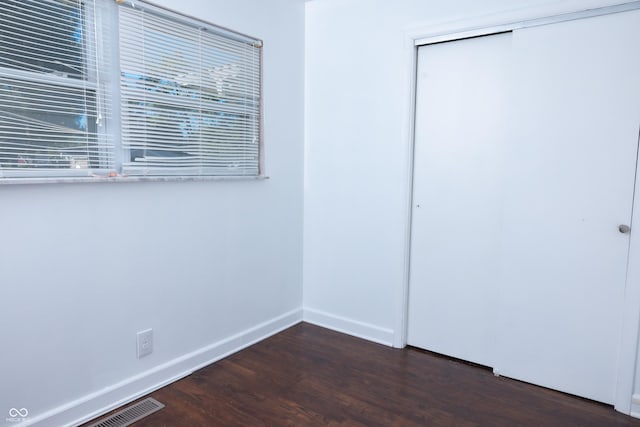 unfurnished bedroom featuring a closet and dark hardwood / wood-style flooring