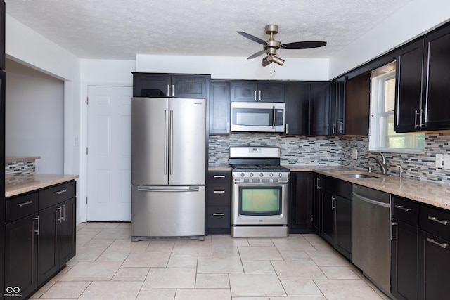 kitchen with ceiling fan, appliances with stainless steel finishes, tasteful backsplash, a textured ceiling, and sink