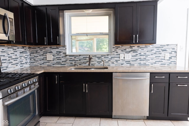 kitchen featuring light stone countertops, sink, appliances with stainless steel finishes, and tasteful backsplash