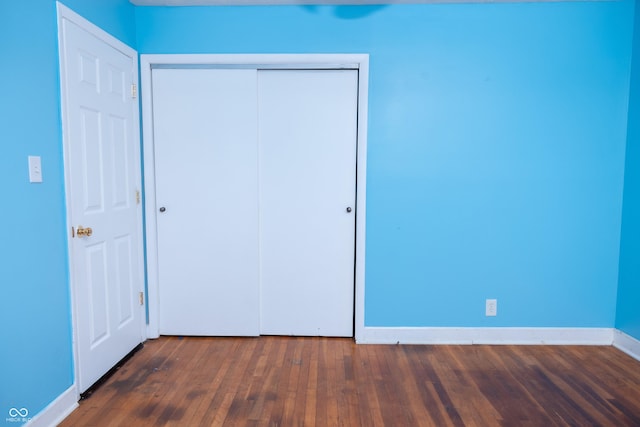 unfurnished bedroom with dark wood-type flooring and a closet