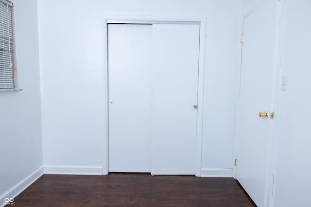 unfurnished bedroom featuring dark hardwood / wood-style flooring and a closet