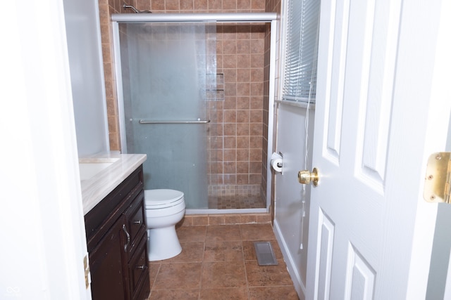 bathroom featuring a shower with door, toilet, and vanity