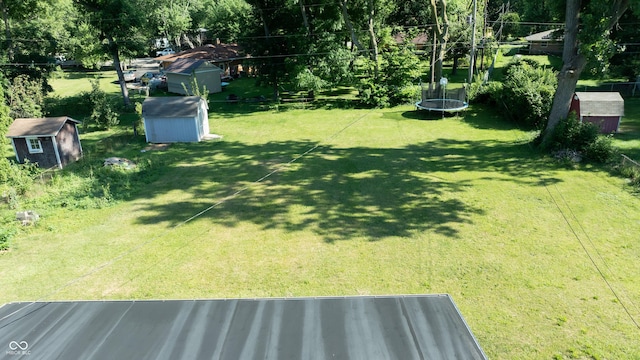 view of yard featuring a trampoline and a storage unit