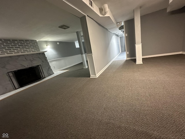 basement with dark carpet and a stone fireplace