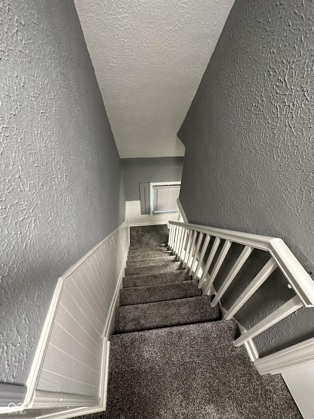 staircase featuring a textured ceiling and carpet