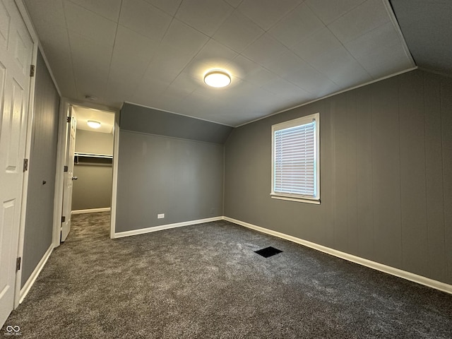 additional living space featuring lofted ceiling and dark colored carpet