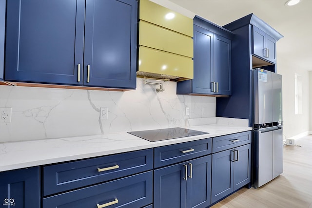 1218 Orange St, Indianapolis, IN 46203 - kitchen with freestanding refrigerator, black electric cooktop, blue cabinets, tasteful backsplash, and light wood-style floors