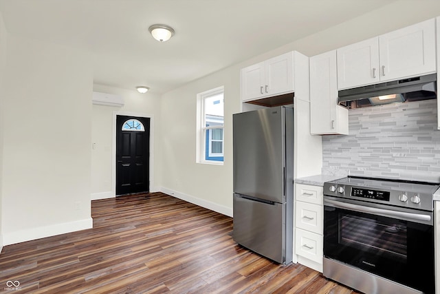 1218 Orange St, Indianapolis, IN 46203 - kitchen featuring appliances with stainless steel finishes, under cabinet range hood, a wall unit AC, backsplash, and dark wood-style flooring