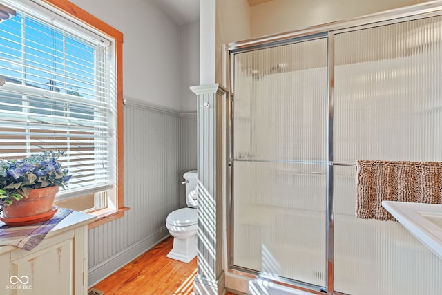 bathroom featuring plenty of natural light, toilet, a shower with door, and wood-type flooring