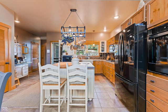 kitchen with a kitchen bar, tasteful backsplash, decorative light fixtures, light tile patterned floors, and black appliances