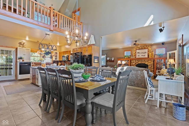 dining area featuring ceiling fan with notable chandelier, a fireplace, light tile patterned flooring, and a towering ceiling