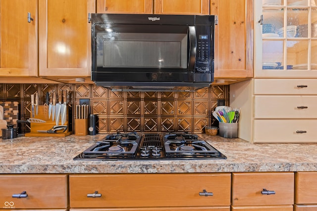 kitchen with light stone counters, decorative backsplash, and black appliances