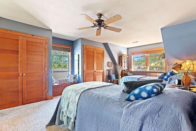 bedroom featuring multiple closets, ceiling fan, carpet floors, and multiple windows