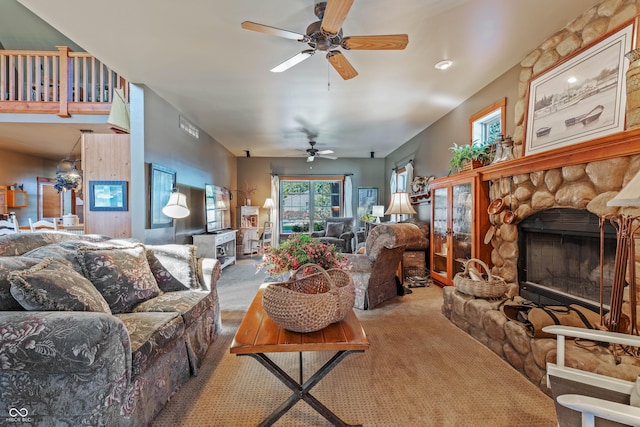 living room featuring a stone fireplace, carpet floors, and ceiling fan