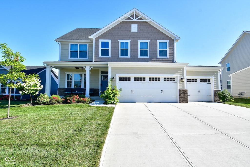 craftsman inspired home featuring a garage, covered porch, and a front lawn