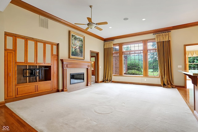 unfurnished living room with ceiling fan, a healthy amount of sunlight, and ornamental molding