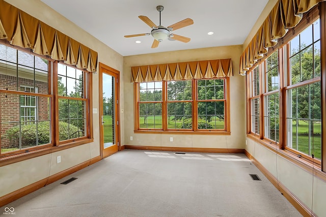 unfurnished sunroom featuring ceiling fan and a healthy amount of sunlight