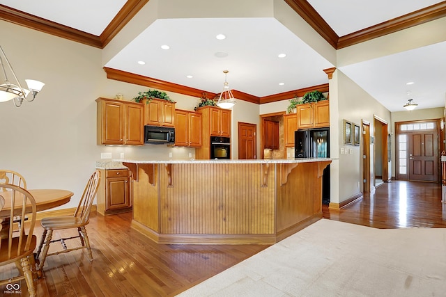 kitchen featuring a kitchen breakfast bar, a large island, black appliances, and decorative light fixtures