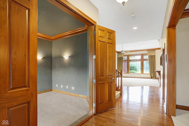 hallway with light hardwood / wood-style floors and ornamental molding