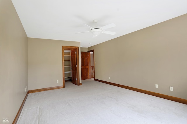 unfurnished bedroom featuring a walk in closet, ceiling fan, a closet, and light carpet