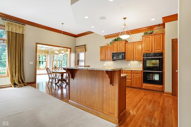 kitchen with a center island, decorative light fixtures, a breakfast bar area, and black appliances