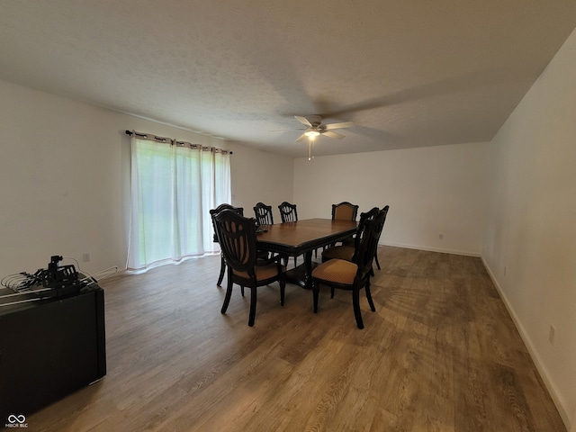 dining space with ceiling fan, hardwood / wood-style flooring, and a textured ceiling