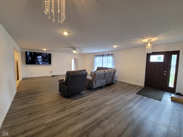 living room featuring dark hardwood / wood-style floors, a textured ceiling, ceiling fan with notable chandelier, and plenty of natural light