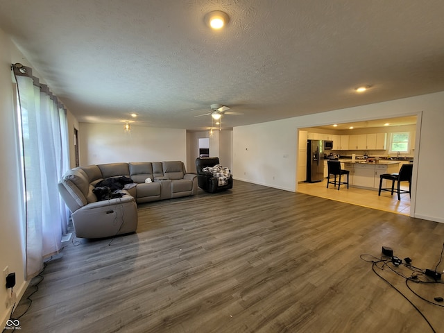 living room with a textured ceiling, dark hardwood / wood-style floors, and ceiling fan