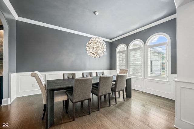 dining area with hardwood / wood-style flooring, a chandelier, and ornamental molding