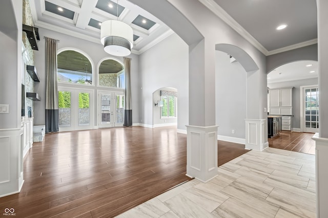 interior space featuring decorative columns, a high ceiling, crown molding, beam ceiling, and coffered ceiling