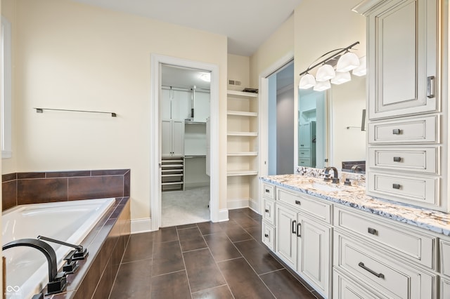 bathroom featuring vanity, tiled tub, and tile patterned flooring