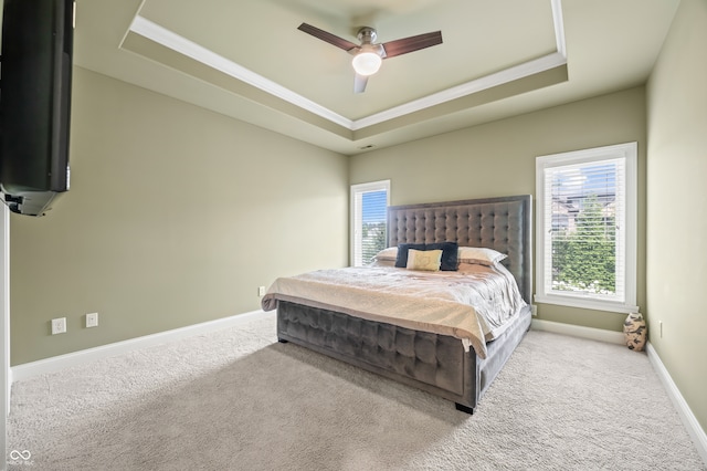 carpeted bedroom with ceiling fan and a tray ceiling