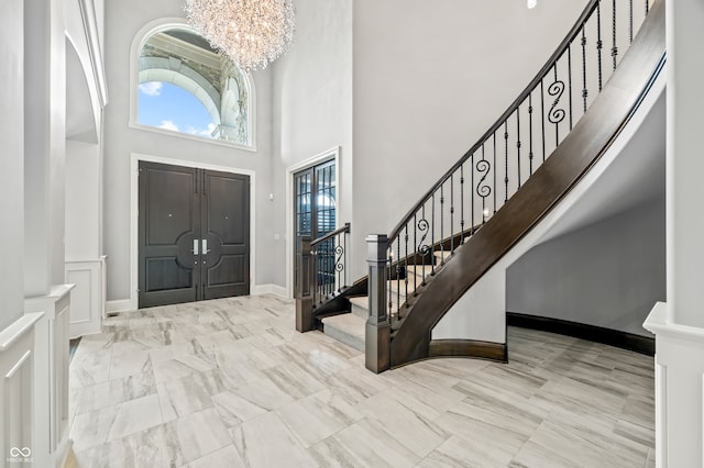 entryway with light tile patterned flooring, a towering ceiling, and a notable chandelier