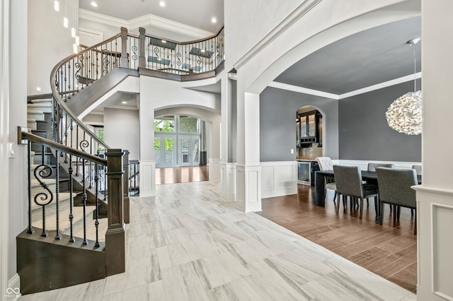 entrance foyer featuring a high ceiling, light wood-type flooring, and ornamental molding