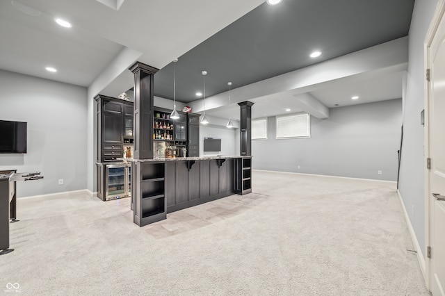 kitchen with pendant lighting, light colored carpet, wine cooler, and light stone countertops