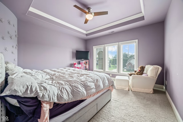 carpeted bedroom with a raised ceiling and ceiling fan