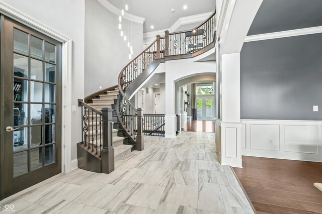 entryway with light hardwood / wood-style floors, crown molding, french doors, and a high ceiling