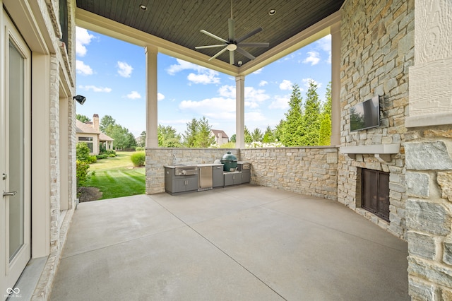 view of patio / terrace with an outdoor stone fireplace, area for grilling, ceiling fan, and a grill