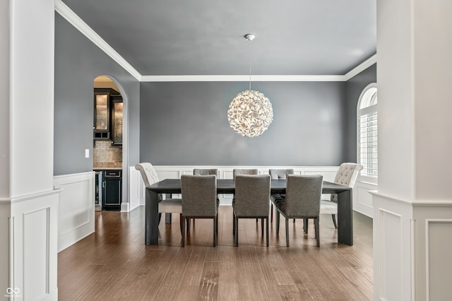 dining space featuring wood-type flooring, crown molding, wine cooler, and an inviting chandelier