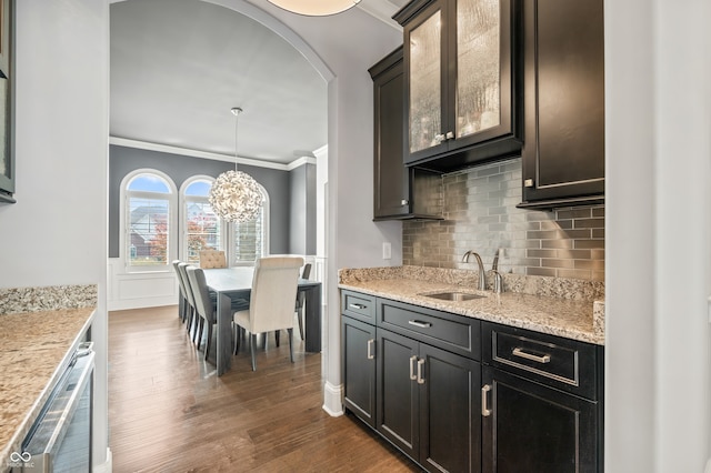 kitchen with a notable chandelier, dark wood-type flooring, decorative backsplash, sink, and ornamental molding