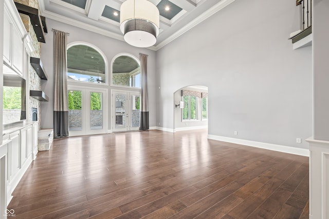 unfurnished living room featuring a towering ceiling, dark hardwood / wood-style flooring, and coffered ceiling