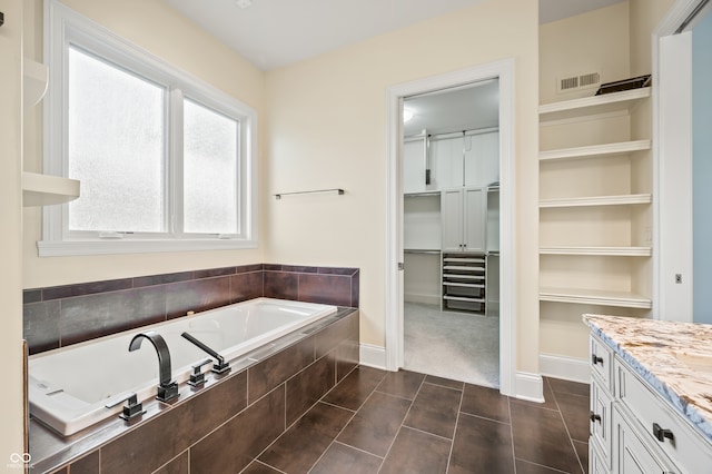 bathroom featuring vanity, tile patterned flooring, and tiled bath