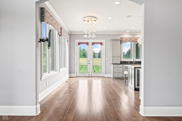 interior space with ornamental molding, beverage cooler, french doors, and hardwood / wood-style floors