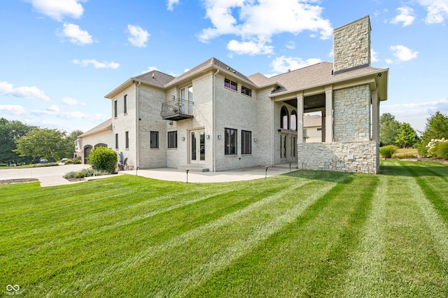 back of property featuring a balcony, a lawn, and a patio area